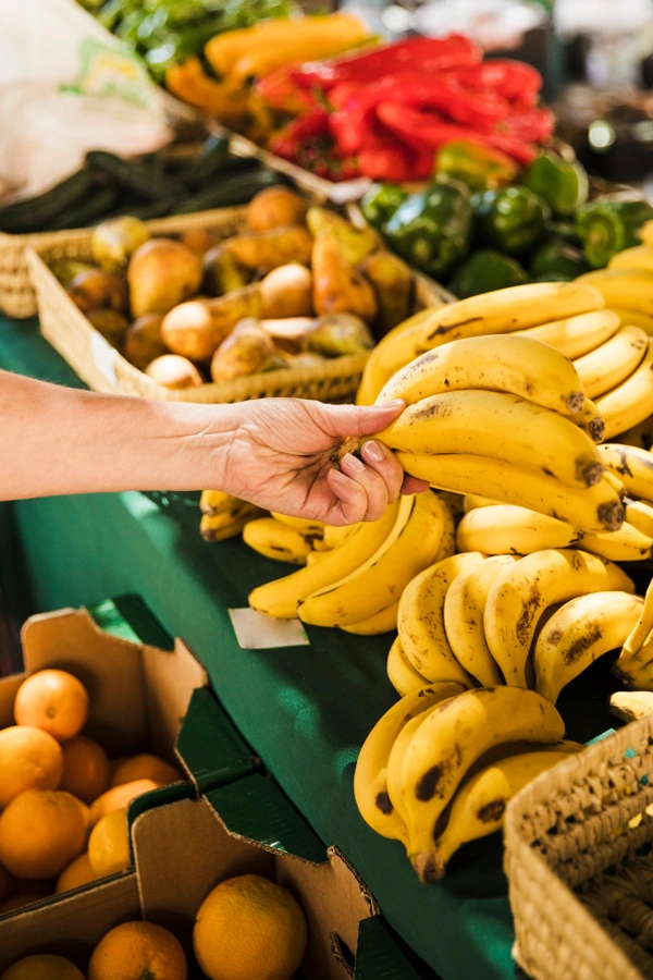 Human hand holding bunch organic fresh banana grocery store